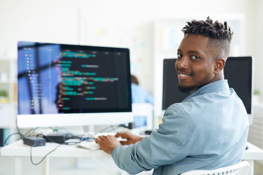 Un homme souriant est assis devant un ordinateur.